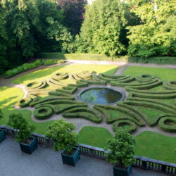 Giardino all’italiana realizzato con siepi di bosso ”Buxus sempervirens” risalente al 1867 circa probabilmente realizzato dal giardiniere Antonio Capello sullo stile preesistente e risalente al progetto di Michel Bernard del 1771 che aveva caratterizzato l’intera superficie del Parco e del Giardino di Agliè. In primo piano cassoni in legno e ghisa contenenti aranci amari “Citrus aurantium” secolari, un tempo situati a Palazzo Reale di Torino.